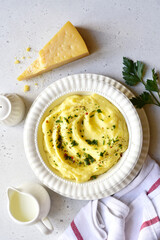 Mashed potato with parmesan cheese and herb in a white bowl . Top view with copy space.