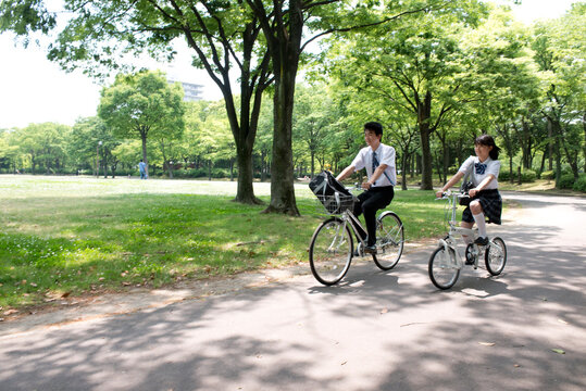 自転車に乗って走る高校生カップル