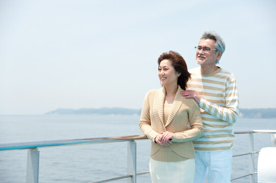 フェリーのデッキで海を見る中年夫婦