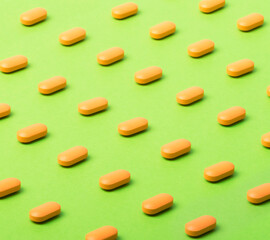yellow pills or capsules lie in rows diagonally on a green background