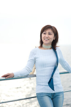 フェリーのデッキから海を見る中年女性