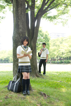 木陰で読書する女子高生と男子高校生