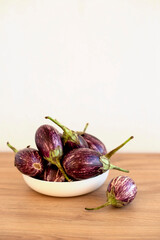 Mini eggplants in a white plate on a wooden table