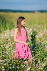 Happy child in field. Beautiful girl in dress in a straw hat