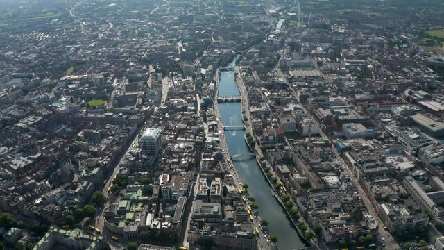 Aerial panoramic footage of Liffey river calmly flowing through city. Large town from height. Dublin, Ireland