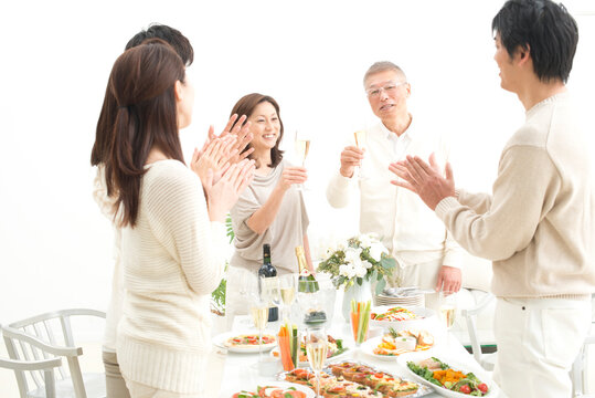 お祝いの拍手をされるシャンパンを飲む中高年夫婦
