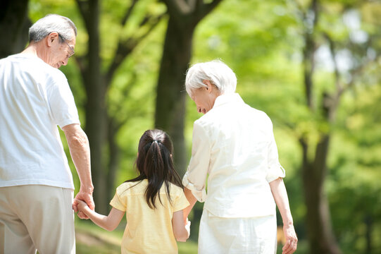 公園を孫と散歩するシニア夫婦