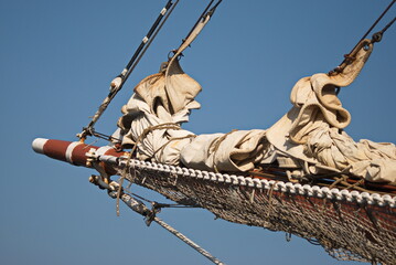 Sailing ship bow, ropes and lowered sails.