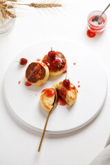 top view of plate with cheese pancake syrniki or cheesecakes with jum on white background