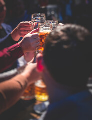 View of beer festival, gold coloured beer glasses assortment in a pub, german unfiltered wheat beer, people cheering up and toasting with glasses of light lager, Oktoberfest view