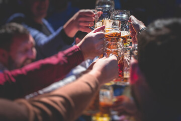 View of beer festival, gold coloured beer glasses assortment in a pub, german unfiltered wheat beer, people cheering up and toasting with glasses of light lager, Oktoberfest view