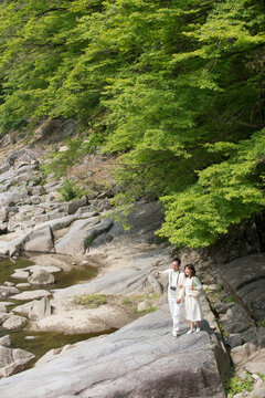 旅行先で川岩を歩く中高年夫婦