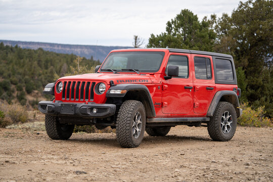 Red Jeep Wrangler Rubicon parked on a dirt road in the wilderness with overcast sky. Taken October 8, 2021 in Telluride, Colorado.