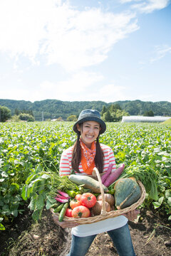 畑で収穫した野菜を見せる女性