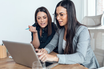 Two beautiful designer women working in a design project while choosing materials in the office.