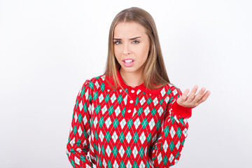 Studio shot of frustrated Young beautiful caucasian girl wearing christmas sweaters on white background gesturing with raised palm, frowning, being displeased and confused with dumb question.