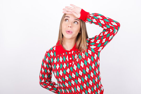 Young beautiful caucasian girl wearing christmas sweaters on white background wiping forehead with hand making phew gesture, expressing relief feels happy that he prevented huge disaster. 