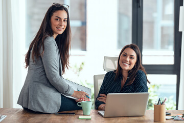 Two beautiful designer women working in a design project while choosing materials in the office.