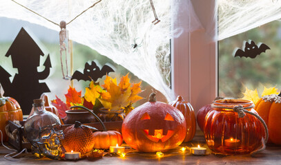 Festive decor of the house on the windowsill for Halloween - pumpkins, Jack o lanterns, skulls,...
