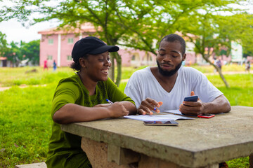 Black university handsome man assisting his female friend with her lecture in the campus. Focus is...