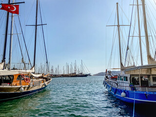 View of the embankment of a resort town in Turkey with boats moored at the pier overlooking the mountains and the sea.