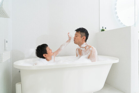 お風呂に入って泡で遊ぶ父と息子