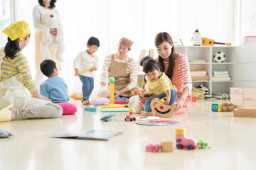 保育園で遊ぶ園児と保育士