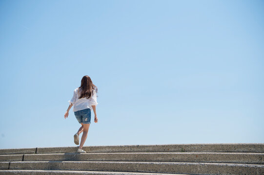 海の堤防に登る女性