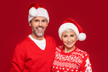 Loving mature couple in santa hats smiling heartily for the camera.