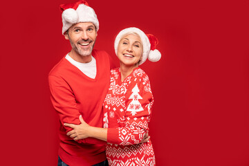 Loving mature couple in santa hats smiling heartily for the camera.
