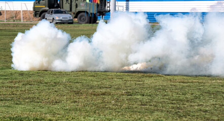 Fototapeta na wymiar A white smoke bomb on green grass in summer.