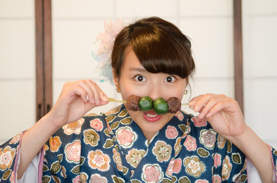 お団子を持っておどけたポーズをする女性