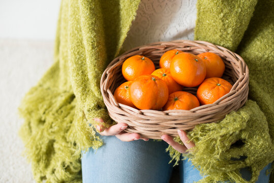 かごに入ったみかんを持つ女性の手