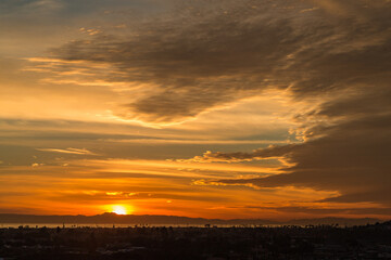 Fototapeta na wymiar Dramatic Cloudy Orange Sunset over the Channel Islands as Seen from Newport Beach Back Bay 
