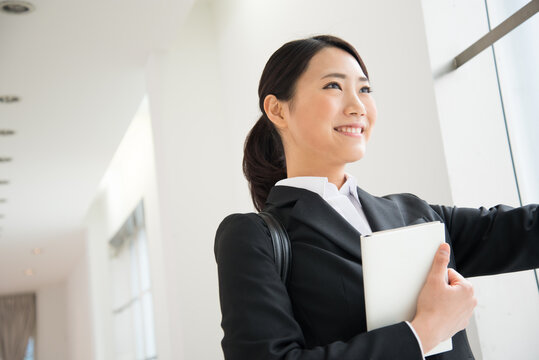 スケジュール帳を持っているスーツ姿の女性