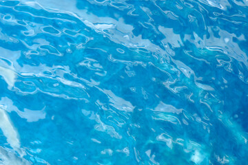 Fototapeta na wymiar Blue water surface. Water waves with sunlight highlights . Transparent blue clear water surface texture with ripples and splashes.