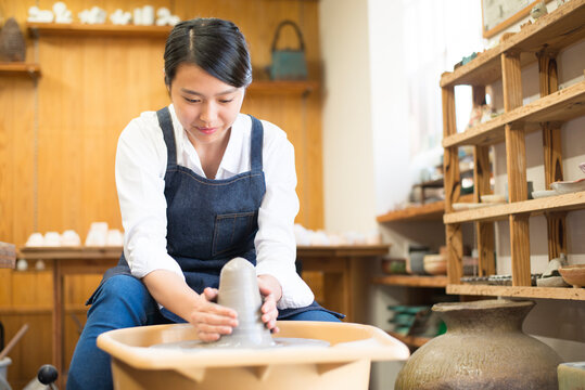 電動ろくろで粘土を触っている女性