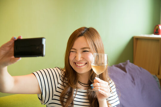 ワイングラスを持って自撮りをしている女性