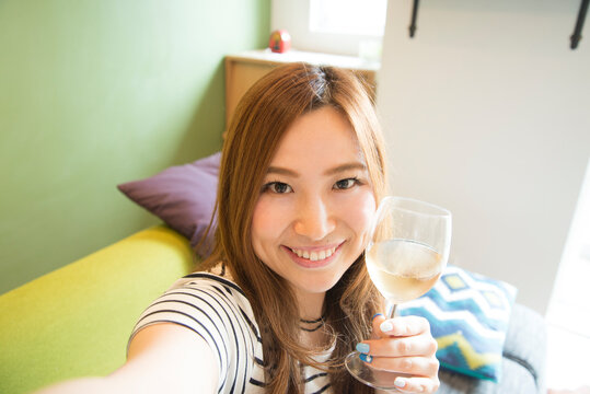 ワイングラスを持って自撮りをしている女性