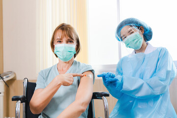 elderly woman patient getting covid-19 or coronavirus vaccine in a wheelchair ​at the hospital.