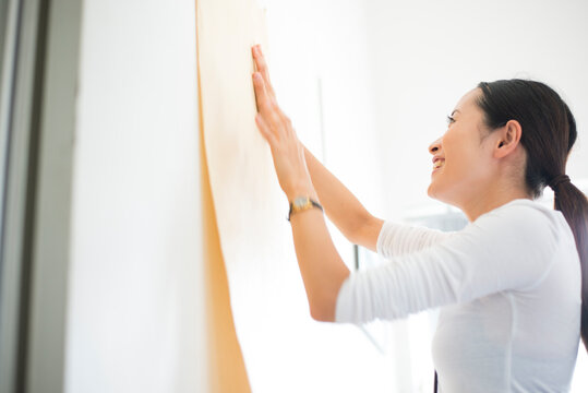 壁に模造紙を貼っている女性