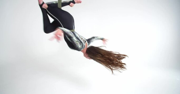 Upside down spin with a split, woman doing aerial silks in white room, 4k