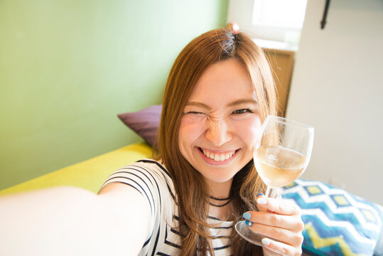 ワイングラスを持って自撮りをしている女性