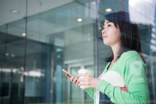 コーヒーを持って遠くをみている女性