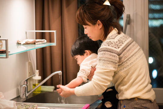 台所で手を洗っている男の子と母親