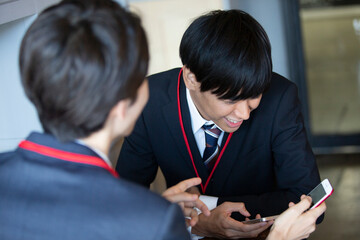 スマホを見せ合う20代男性2人