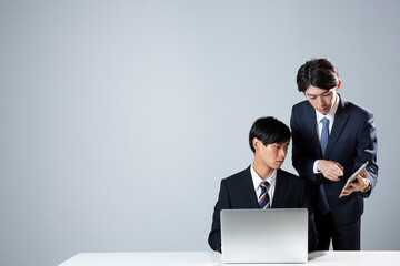 パソコンを指差し説明をするスーツ姿の男性2人