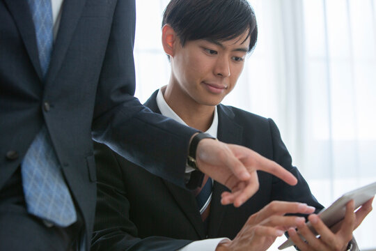 タブレットを使い説明を受けるスーツ姿の男性