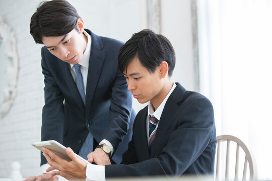 タブレットを使い説明を受けるスーツ姿の男性