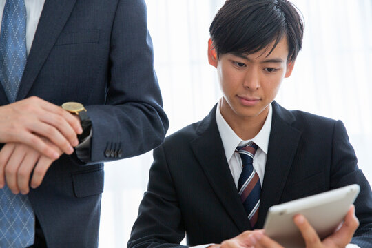 タブレットを使い説明を受けるスーツ姿の男性